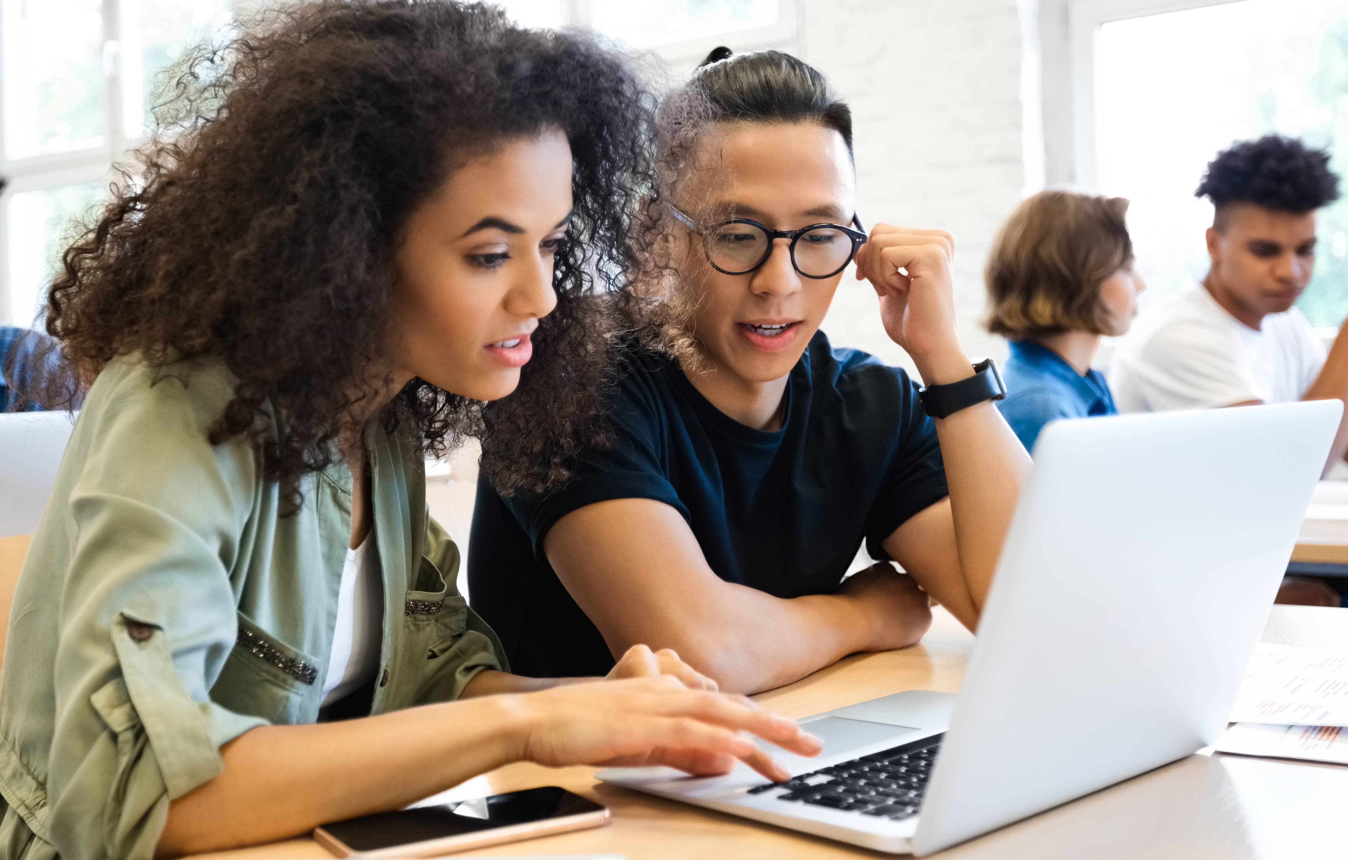 Two students huddled around a laptop